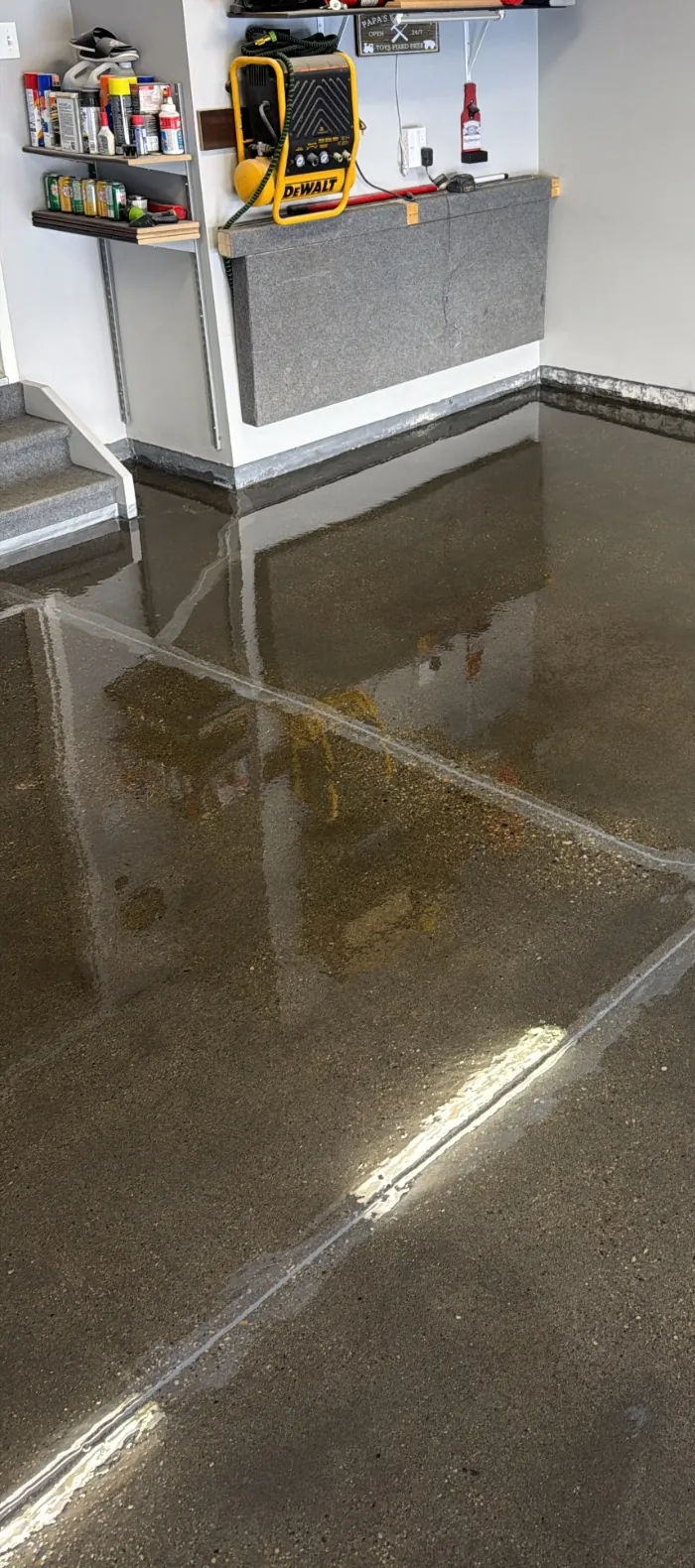 Fresh 100% solids epoxy base coat being spread across a concrete garage floor